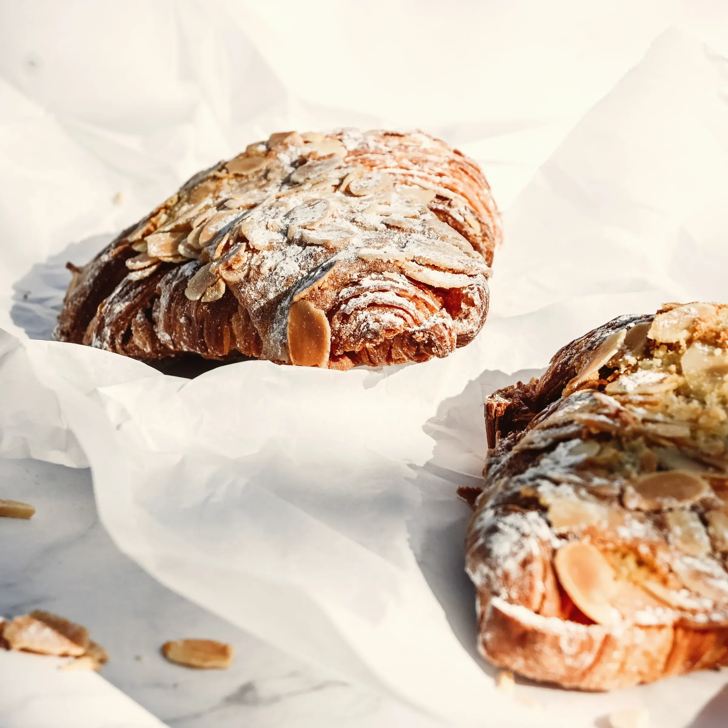 Almond croissants covered in toasted sliced almonds on baking paper