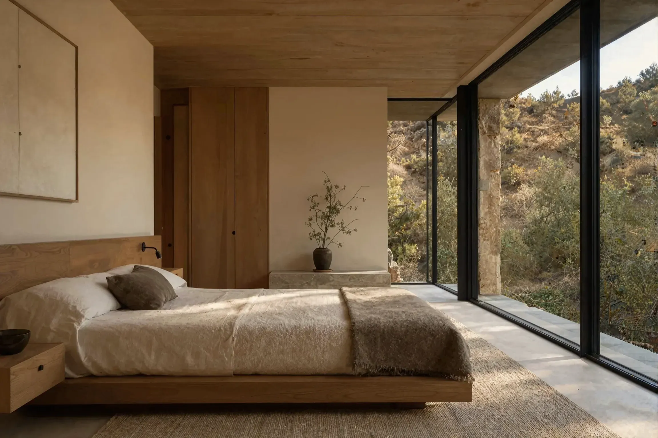 A quiet bedroom with a low oak bed and a glass wall onto the hillside