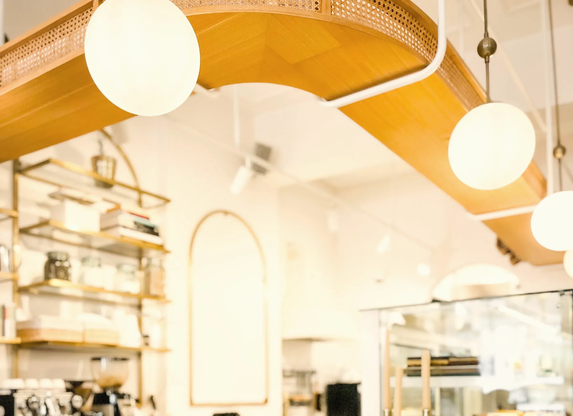 A bright bakery counter under globe lamps, with arched shelves behind