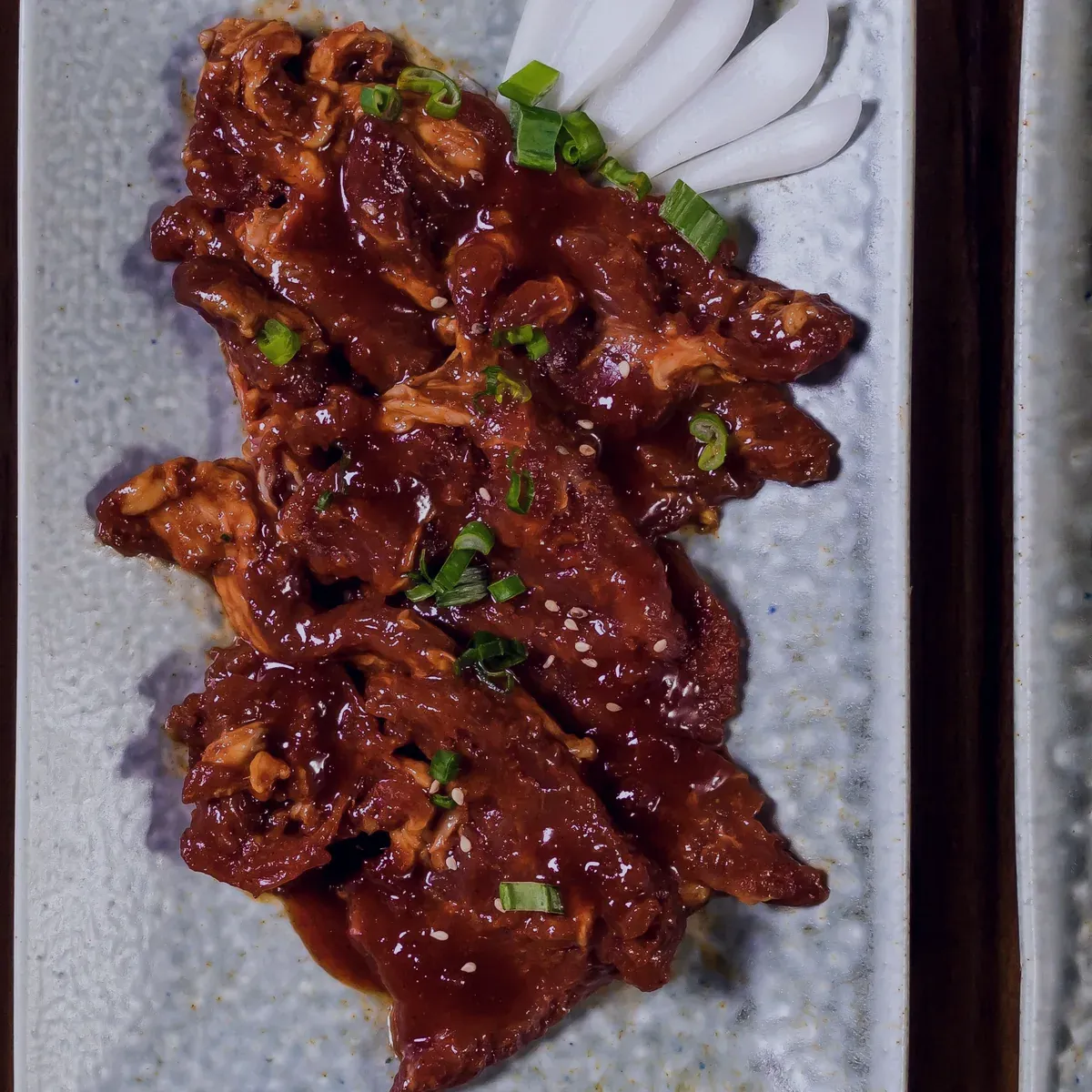 Spicy marinated chicken pieces on a speckled plate