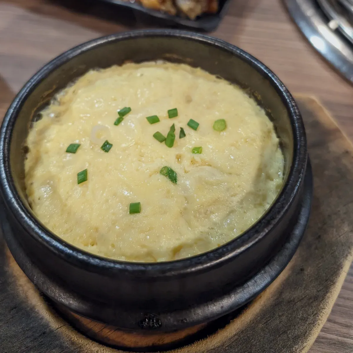 Fluffy steamed egg in a small black earthenware pot