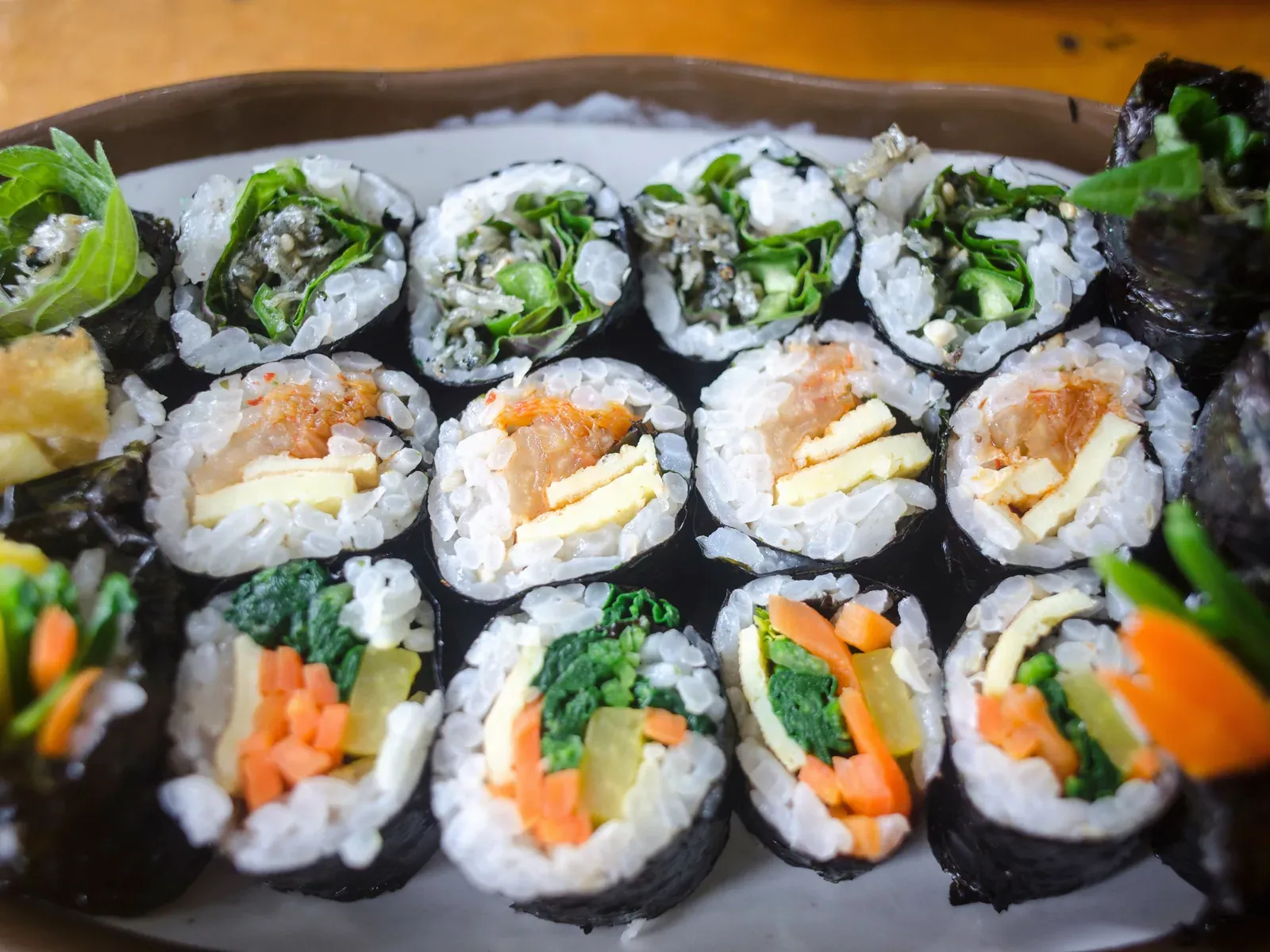 Three kinds of kimbap sliced into rounds, showing radish, spinach, egg and carrot inside