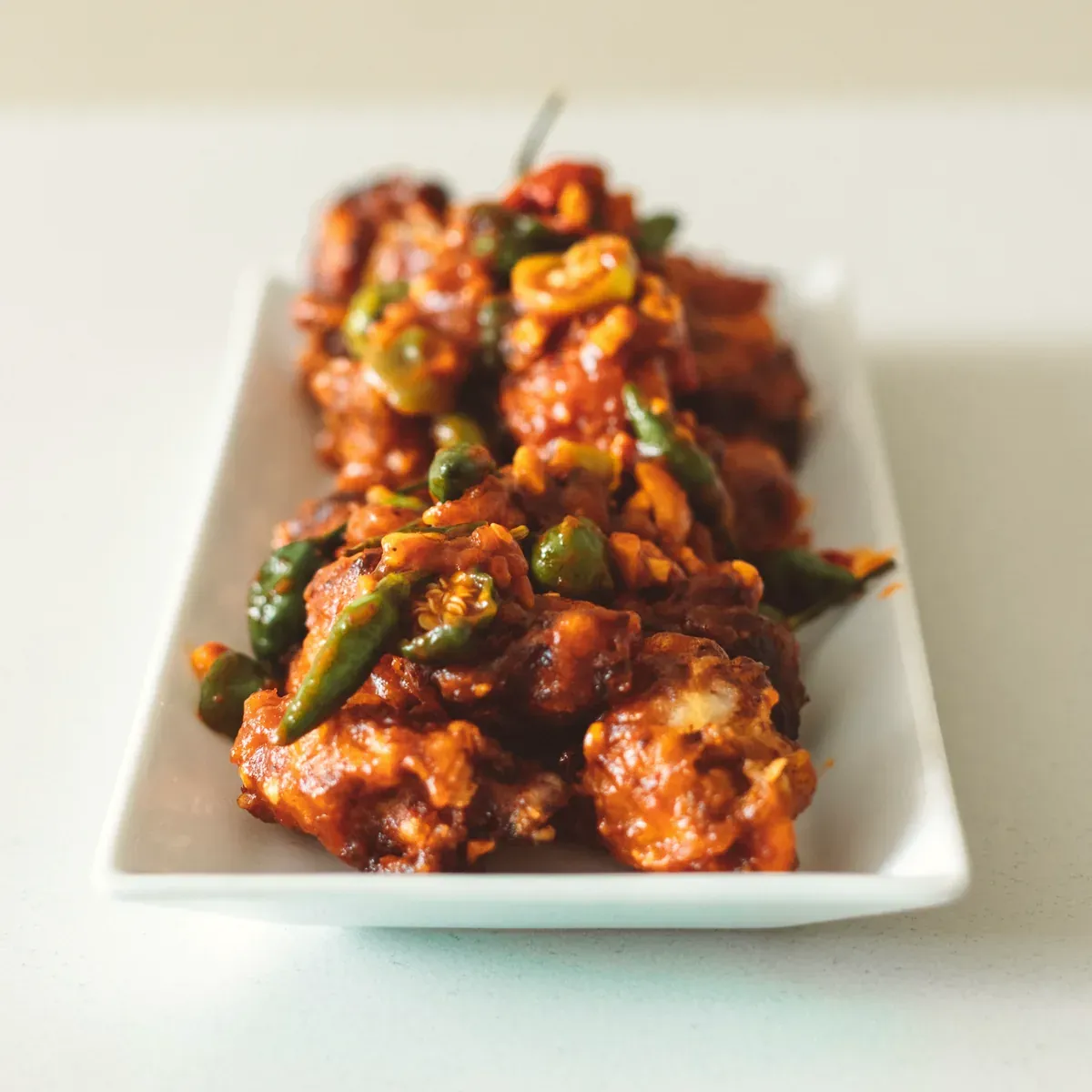 Crispy chicken pieces in a red garlic chili glaze with green chilies