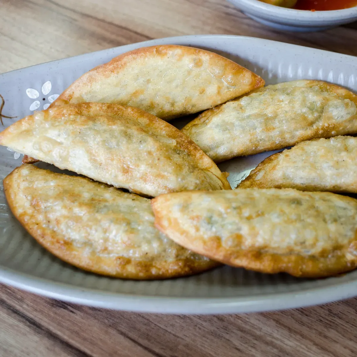 Pan-fried dumplings, golden and crisp, on a pale ceramic plate