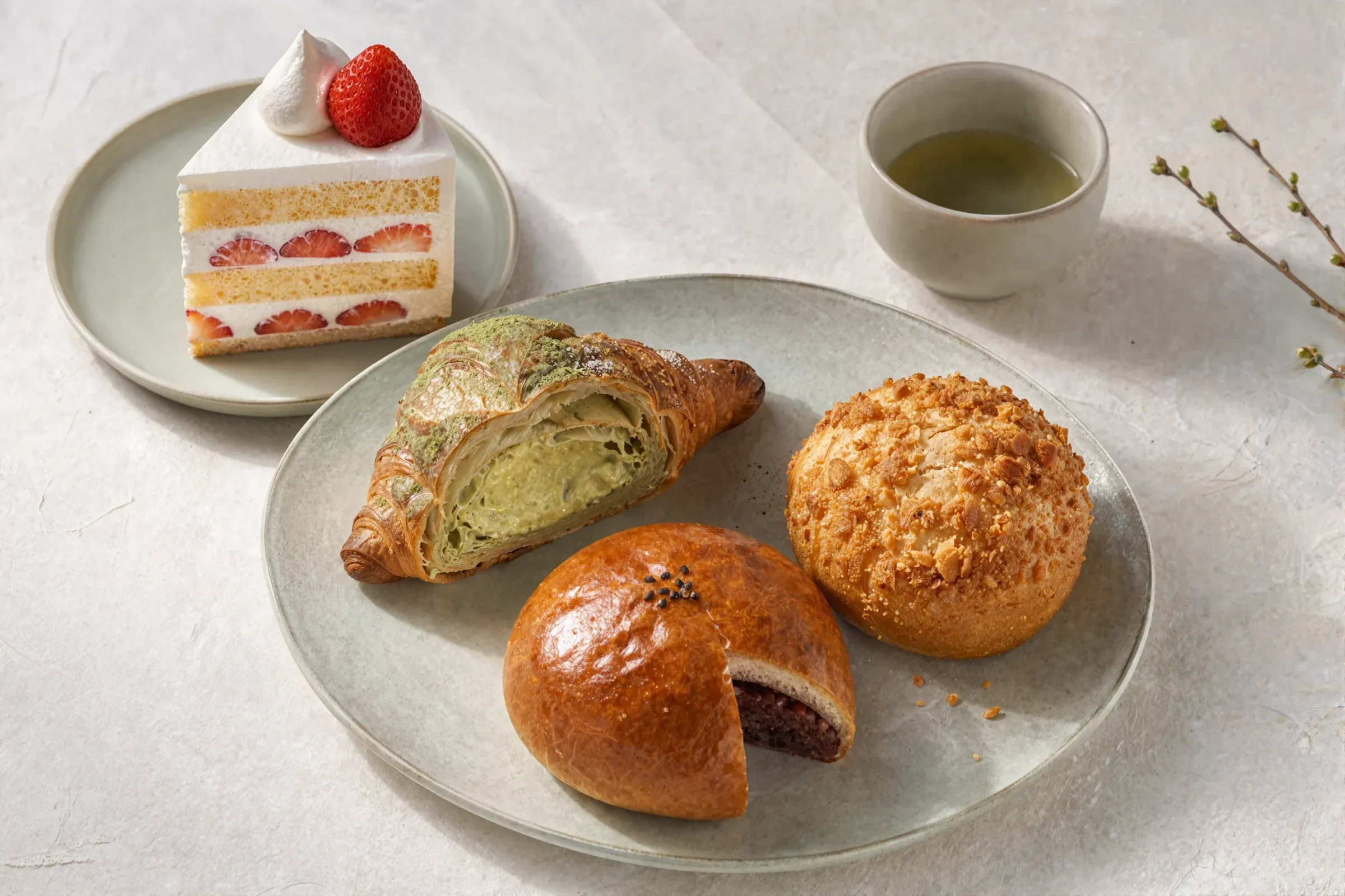 A matcha cream croissant, a soboro bun and a red bean bun on a plate