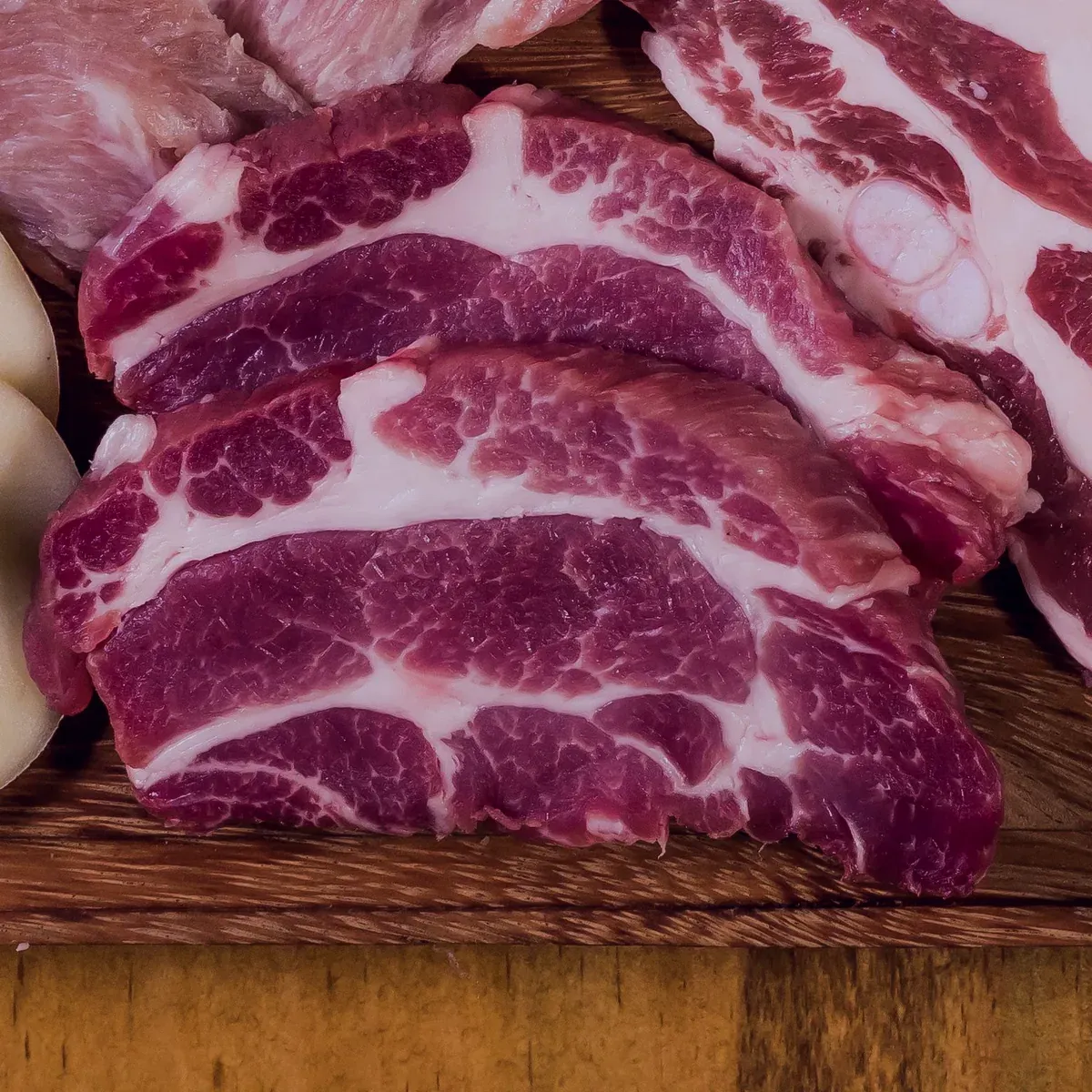 Marbled pork collar steaks on a wooden board