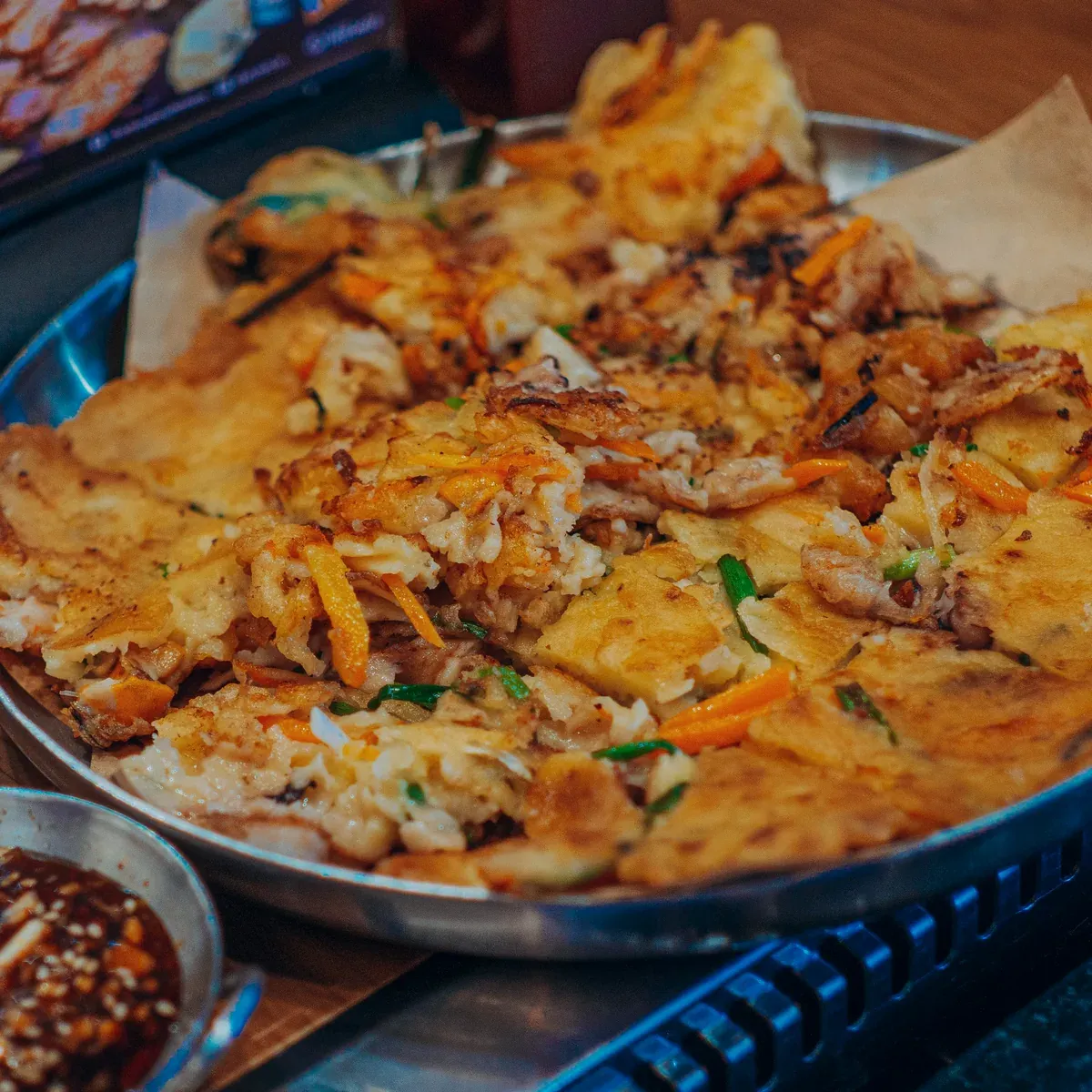 Crispy seafood scallion pancake on a steel tray