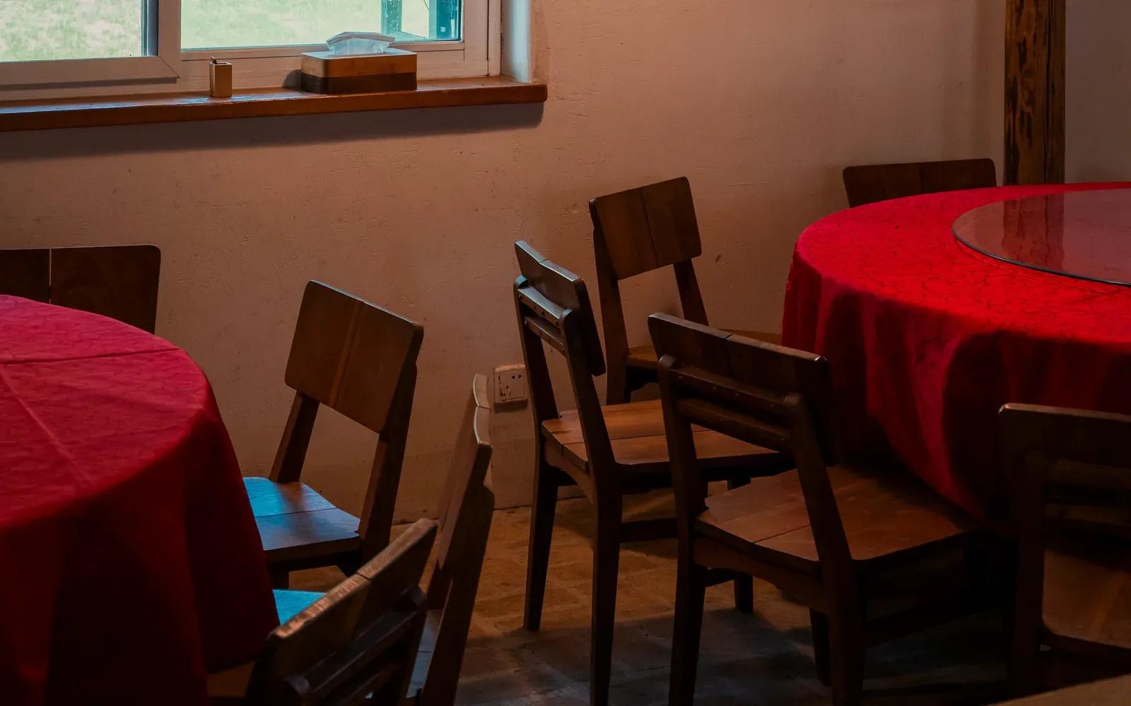 A private room with two round tables in red cloths and a glass lazy susan