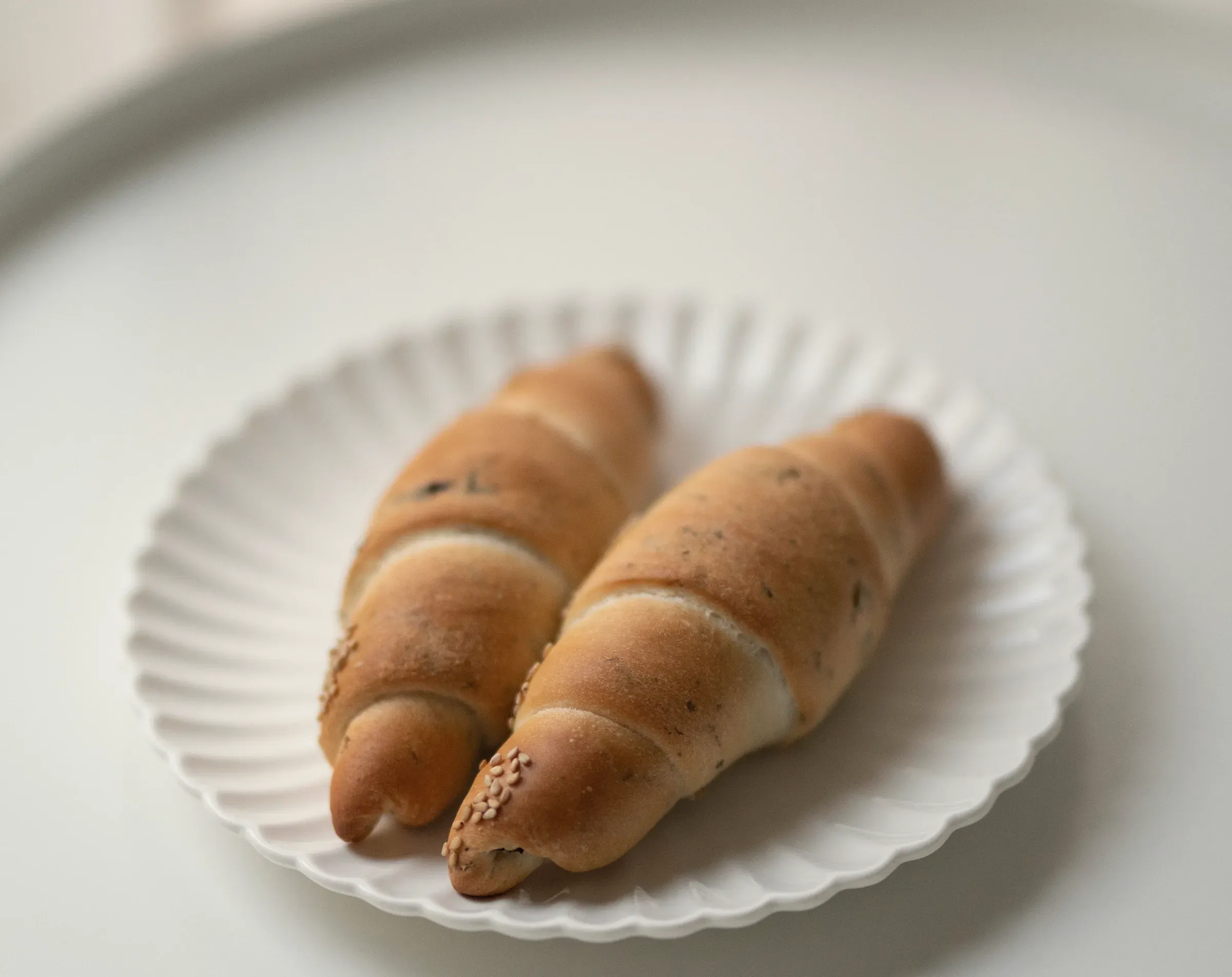 Two salt butter rolls on a fluted white plate