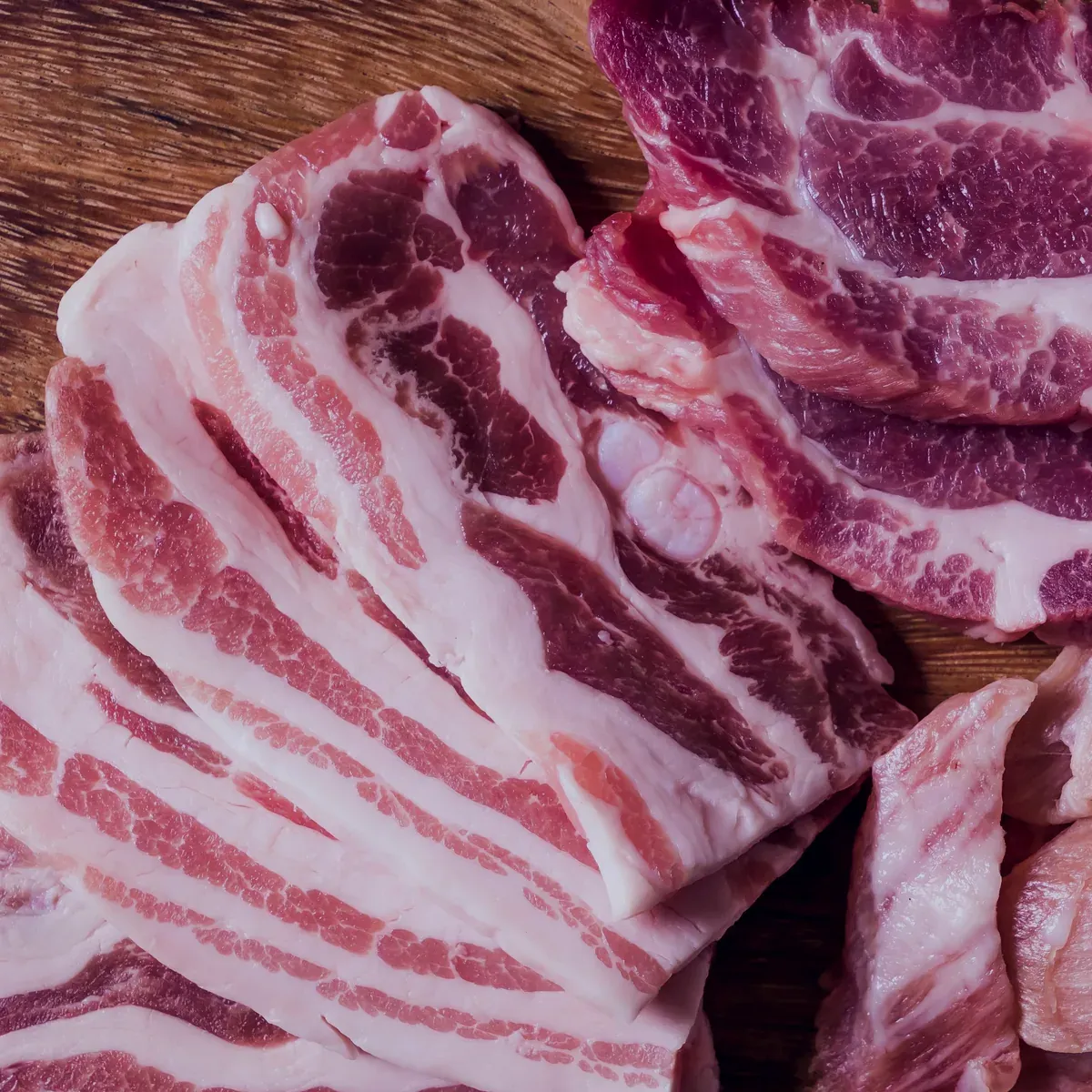 Raw pork belly slabs with pork collar on a wooden board