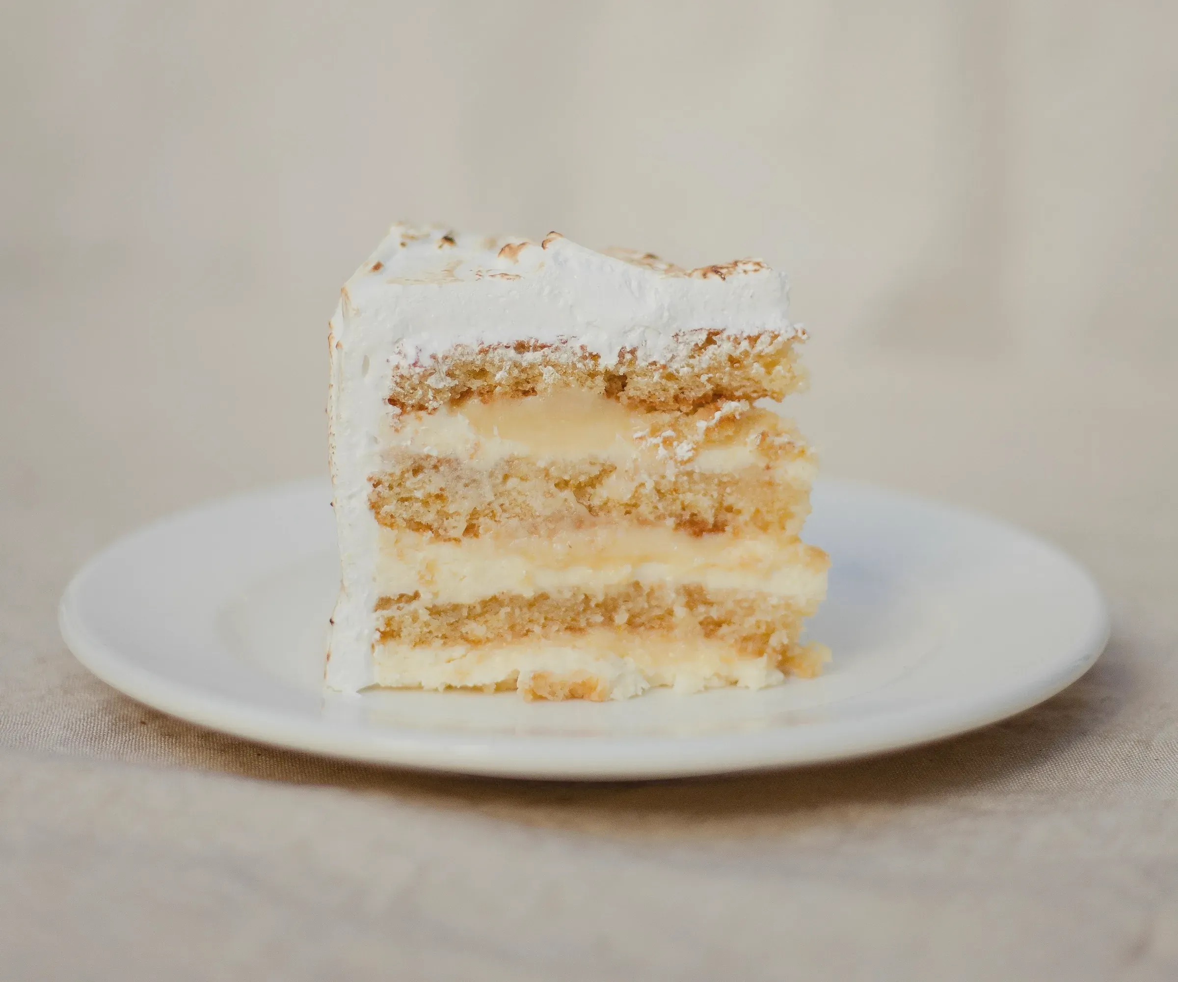 A slice of vanilla layer cake showing pale sponge and cream