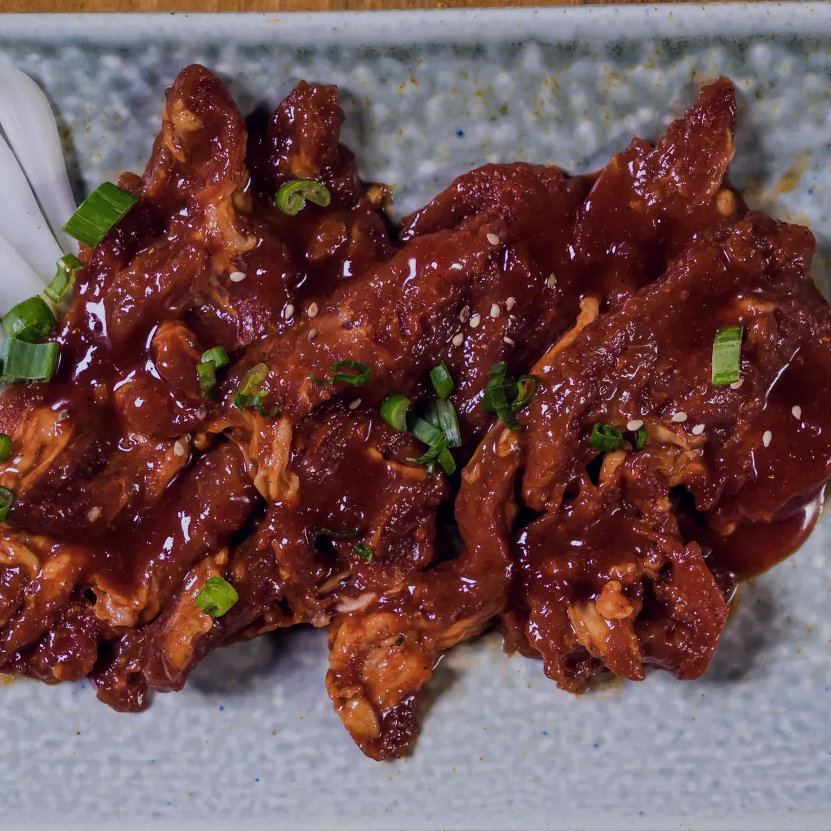 Gochujang pork with scallion on a speckled plate
