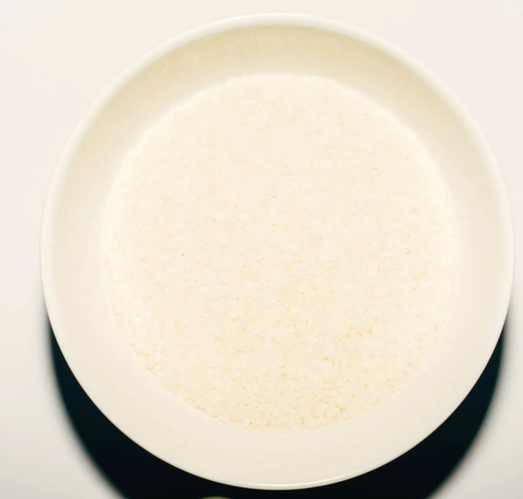 A wide white bowl of smooth white rice porridge, from above