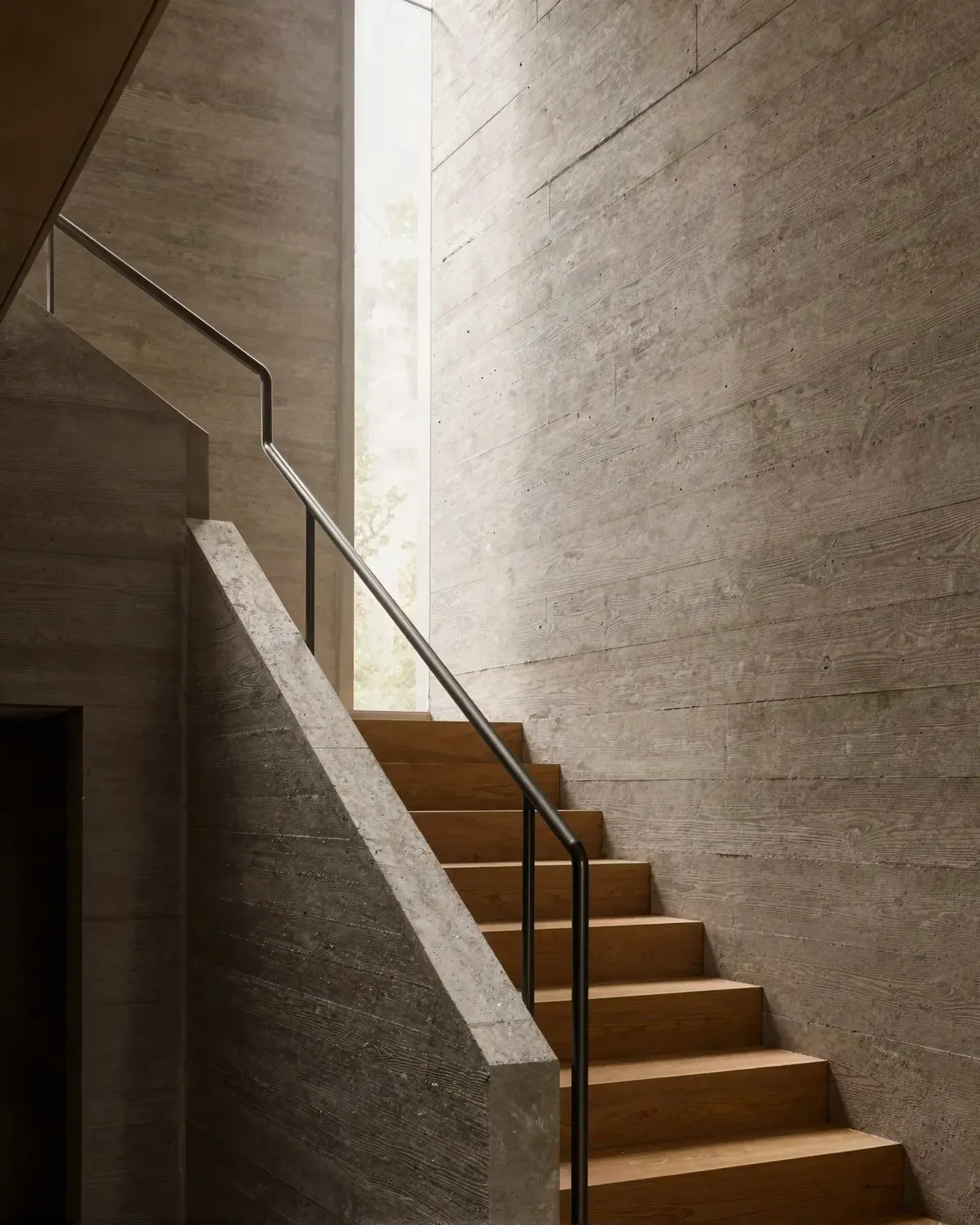 A concrete stair lit from a tall skylight