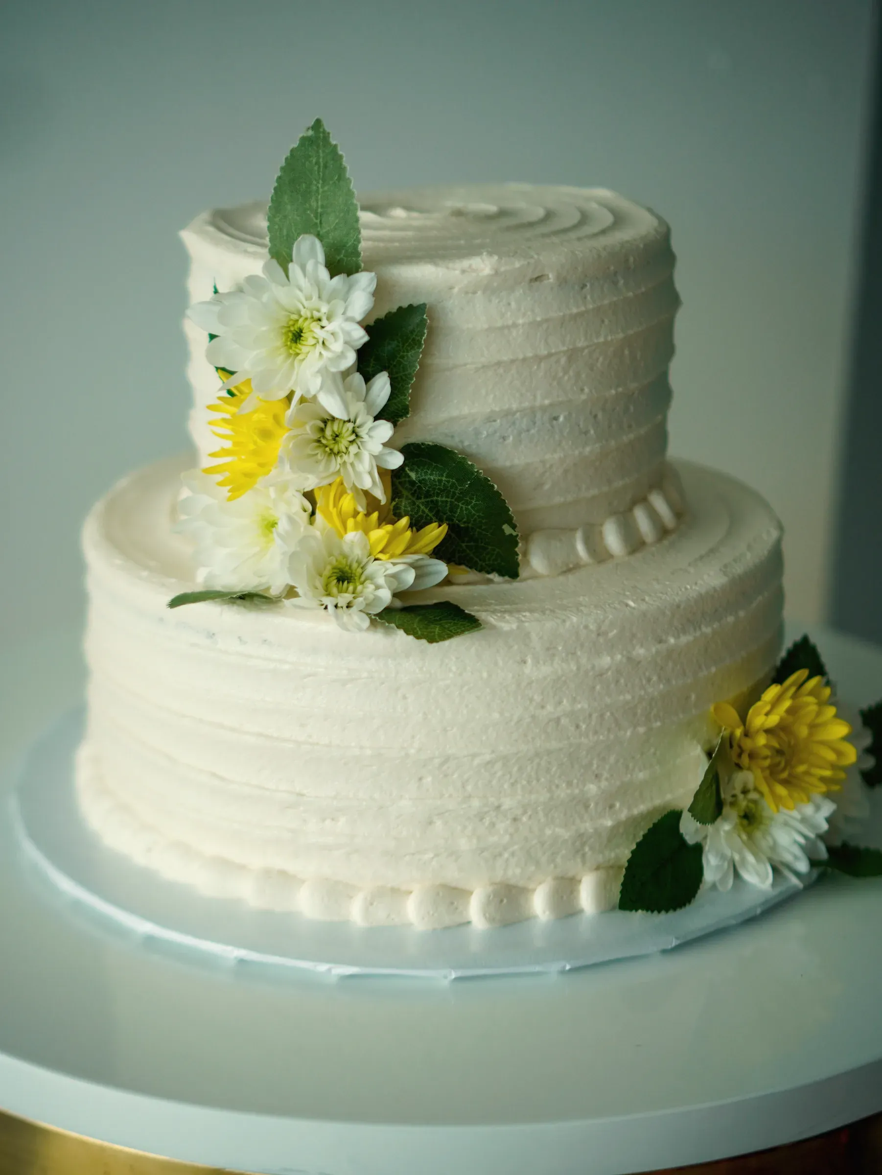 A two-tier buttercream cake dressed with fresh flowers